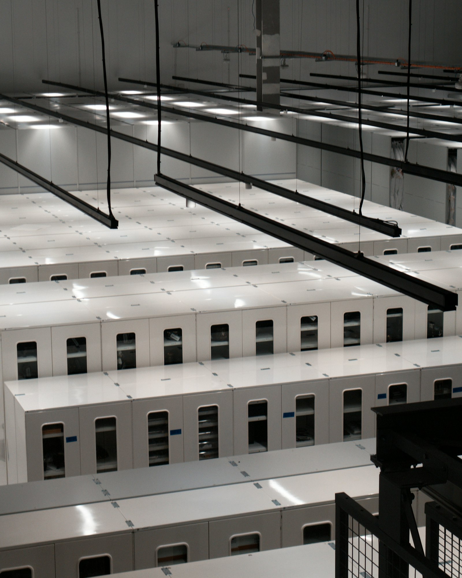 Rows of white server cabinets in a large data center hall, seen from above